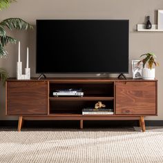 a flat screen tv sitting on top of a wooden entertainment center next to a potted plant