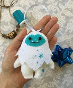 a hand holding an ornament with a blue star on it and a white face