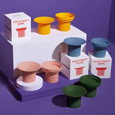 an assortment of colorful cups and bowls on display in front of a purple background with the words teeth party bowl