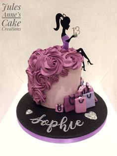 a pink and black cake with a woman on it's top is sitting on a table