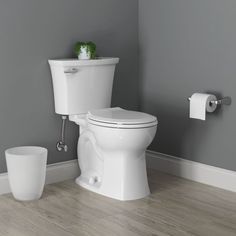 a white toilet sitting in a bathroom next to a roll of toilet paper on the wall