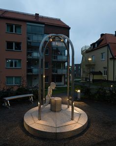 a sculpture in the middle of a courtyard with lights shining on it's sides