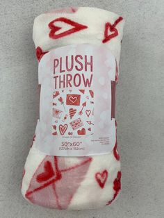 a red and white blanket with hearts on it that says plush throw in the middle