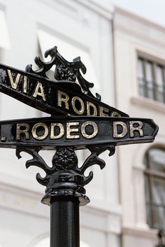 two street signs on top of a black pole in front of a large white building