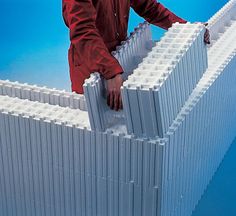 a man standing on top of a building made out of lego blocks with his hands on the wall