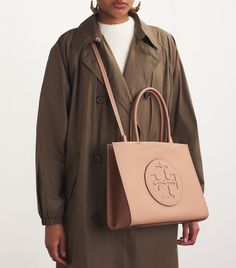 Find TORY BURCH Small Ella Tote Bag on Editorialist. Youve probably heard about Tory Burchs Ella bag, the carry all tote whose boxy shape captured the hearts of busy New Yorkers. Here, the style and functionality of the original are fully preserved, while the fabrication now consists of an innovative leather alternative that is durable, rich and fade-resistant. Made from Bio Fabbrica Bio-Tex, the bags material contains 64% certified bio-based content, engineered with non-GMO plant protein grown in North America. The Ella Bio was developed in partnership with Modern Meadow, an American biotechnology company on the cutting edge of sustainable material innovation. Tory Burch Ella Tote, Ella Tote, Tory Burch Ella, Tory Burch Tote, Stylish Tote Bag, Work Tote, Small Tote Bag, Plant Protein, Bag Light