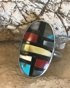 Vintage sterling Zuni ring with stone to stone inlay of coral, turquoise, shell, and onyx. There are slight gaps in places in the inlay. The ring is interesting, and I believe old. The artisan has chosen to include more gray matrix than turquoise in one panel. This is a soulful and colorful little artisan made ring. The ring is size 6-1/4. The face of the ring is .75 inches long and .47 inches wide. It weighs 3 grams. Handmade Artisan Multicolor Turquoise Ring, Handmade Multicolor Artisan Turquoise Ring, Artisan Oval Multi-stone Turquoise Ring, Artisan Multicolor Turquoise Ring With Natural Stones, Artisan Multicolor Turquoise Ring, Handmade Multicolor Southwestern Turquoise Ring, Multicolor Oval Inlay Rings, Oval Multicolor Rings For Collectible, Oval Multicolor Rings With Inlay