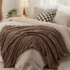 a bed covered in brown blankets and pillows