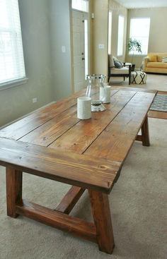 a wooden table sitting in the middle of a living room with two vases on top of it