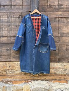 Here's an oversized coat for women or men in a patchwork of dark blue denim, lined with an orange polyester fabric with black checks.  Bordered by a jeans belt collar with belt loops and buttonhole inserts.  Frayed, raw-edge sleeves and hem.  Original breast pocket on right Left front patch pocket and inside jeans pocket. Original built-in pocket and patch pockets on back. One size fits all  Shoulder/bottom length front 42,9" (109 cms) Neck length / back hem 42,1" (107 cms) Chest width 28,7" (73 Oversized Dark Wash Outerwear With Patchwork, Oversized Denim Blue Patchwork Outerwear, Medium Wash Oversized Outerwear With Patchwork, Oversized Medium Wash Outerwear With Patchwork, Dark Wash Recycled Denim Outerwear With Patchwork, Blue Patchwork Outerwear In Recycled Denim, Blue Recycled Denim Patchwork Outerwear, Blue Recycled Denim Outerwear With Patchwork, Recycled Denim Outerwear With Patches For Fall