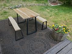 a wooden table and bench sitting on top of a rug next to a potted plant