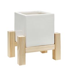 a white planter sitting on top of a wooden stand