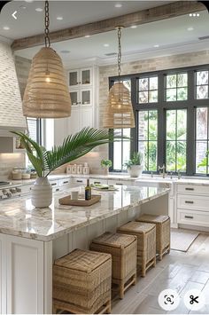 a large kitchen with white cabinets and marble counter tops, two hanging lights above the island