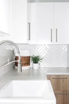 a white kitchen with herringbone tile backsplash