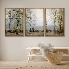 three paintings hanging on the wall above a bench in front of a basket with feathers