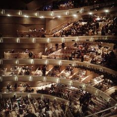 an auditorium filled with lots of people sitting and standing in it's seats at night