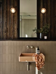 a bathroom sink sitting under a mirror next to a wooden wall