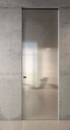 an empty room with a large glass door and concrete walls, in front of a window