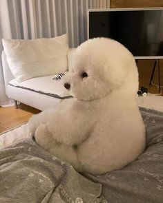 a large white teddy bear sitting on top of a bed