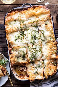 a casserole dish with cheese and herbs on top, next to two plates