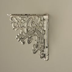 the corner of a metal object with decorative designs on it's side, against a gray background