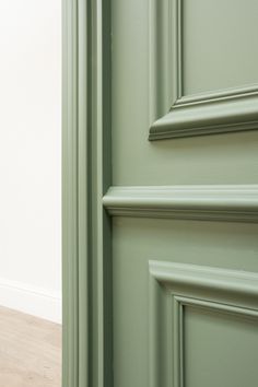 the corner of a room with green painted walls and wood flooring, along with an open door