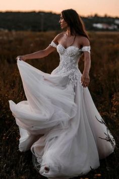 a woman in a white dress is walking through the grass with her hands on her hips