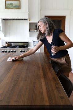 a woman standing at a kitchen counter with her hand on the edge of the table