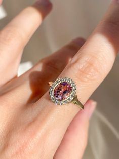 a close up of a person's hand with a ring on their finger and an oval shaped pink diamond in the middle