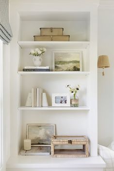 a white shelf filled with books and vases on top of it's shelves