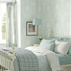 a bedroom with blue and white bedding, pillows and blankets on the bedspread