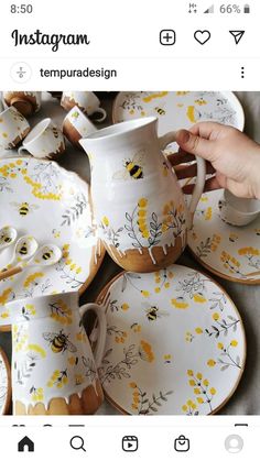 a person is holding a coffee cup and saucer in front of a bunch of plates