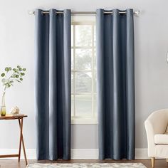 a living room with blue curtains and a white chair in front of a large window