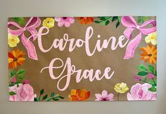 a sign with flowers painted on it that says caroline grace in pink and orange