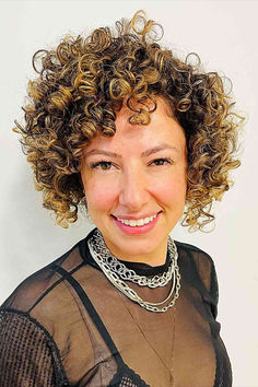 Woman with a jaw-length curly bob enhanced with blonde highlights Bobs With Highlights, Curly Hair With Blonde Highlights, Hair With Blonde Highlights, Bob With Highlights