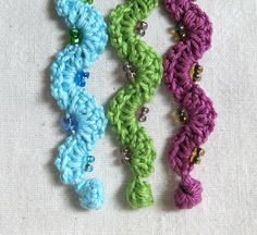 three crocheted bracelets with beads on them sitting next to each other in different colors