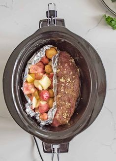 a meatloaf in a slow cooker with potatoes and tomatoes