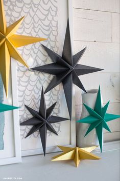 three paper stars are hanging on the wall next to a vase and framed photograph in front of it