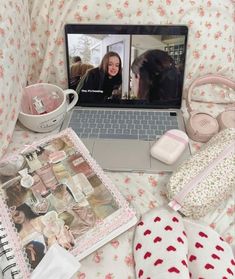 an open laptop computer sitting on top of a bed covered in pink and white flowers