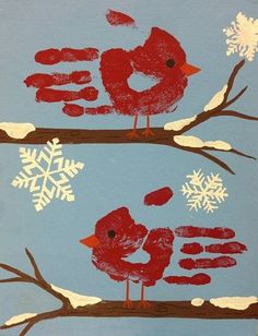 two red birds sitting on top of a tree branch with snowflakes in the background