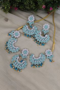 a necklace and earring set with blue beads on a white tablecloth next to flowers