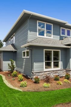 a large gray house sitting on top of a lush green field