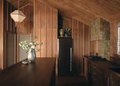 a kitchen with wood paneling and an island in the middle is shown, along with a vase filled with flowers