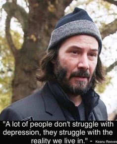 a man with long hair wearing a beanie and looking at the camera while standing in front of a tree