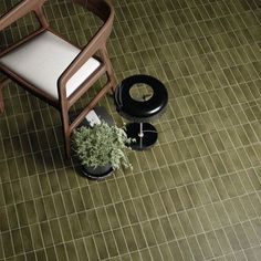 a chair and potted plant sitting on the ground in front of a tiled floor