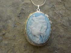 Beautiful Grecian Charioteer cameo locket!!!  The cameo is a gorgeous white on sky blue, beautifully detailed!!!  The locket is victorian style with beautiful scroll on the front and back about 1 3/4" long.  It can hold two photos, keepsakes, or even your daily medication or vitamins!!! Pass down from generation to generation!!! The chain is 22"  1.2mm .925 plated snake chain with a lobster claw clasp!!! Perfect  for Brides or Bridal parties.  Makes a unique memorable gift for any occasion!!!  T Blue Cameo Jewelry For Wedding, Blue Cameo Necklace For Wedding, Blue Medallion Necklace For Wedding, Blue Medallion Necklaces For Wedding, Grecian Women, Cameo Locket, Bridal Parties, Cameo Jewelry, Mermaid Necklace