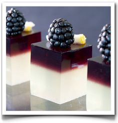 three desserts with blackberries and cream on them are arranged in cubes to look like they're ready to eat