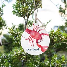 a ceramic ornament hanging from a tree with the name portland painted on it