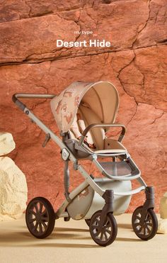 a baby stroller sitting in front of a rock wall with the words desert hide written on it