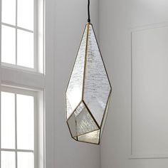 a light fixture hanging from the ceiling in a room with white walls and wooden floors